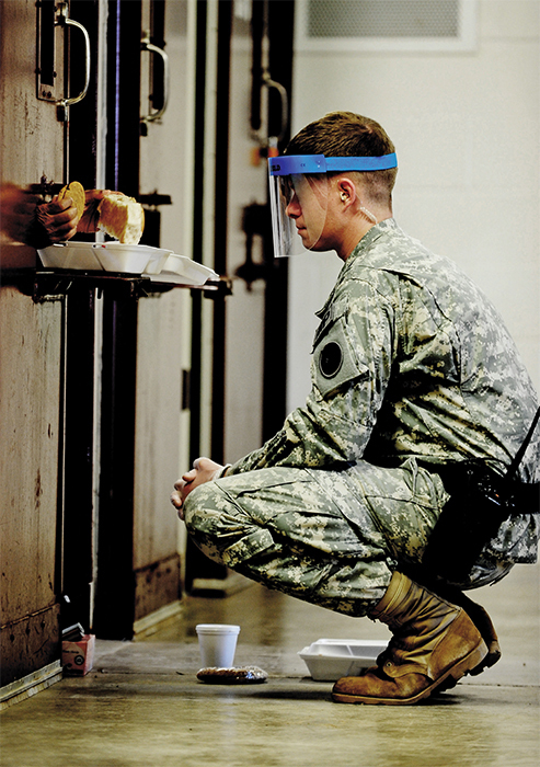 A guard monitoring a detainee eating lunch at the Guantánamo Bay prison camp, 2011.