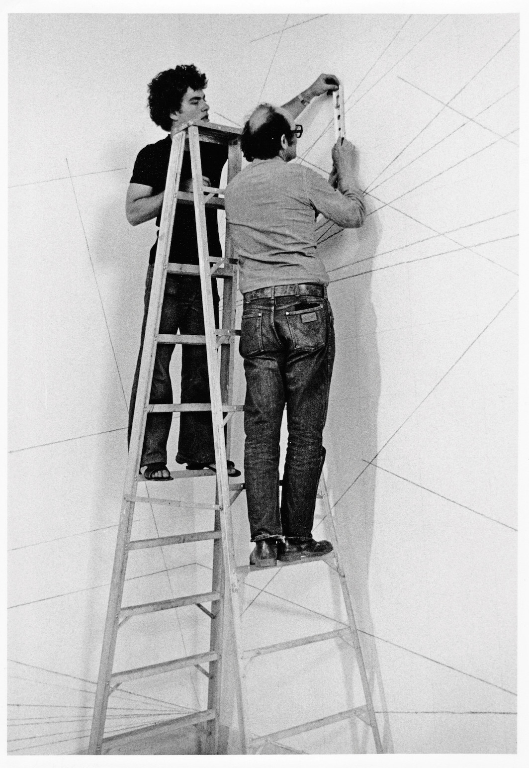 Sol LeWitt and assistant installing LeWitt's Wall Drawing #273: A 6-inch grid covering the walls. Lines from corners, sides, and center of the walls to random points on the grid, 1975, Israel Museum, Jerusalem.